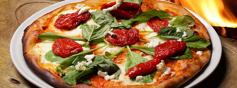 Nygräddad italiensk pizza med soltorkade tomater, basilika och ost.